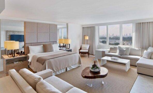 Luxurious hotel suite with a king-size bed, comfortable seating area, and city views, perfect for a relaxing getaway.