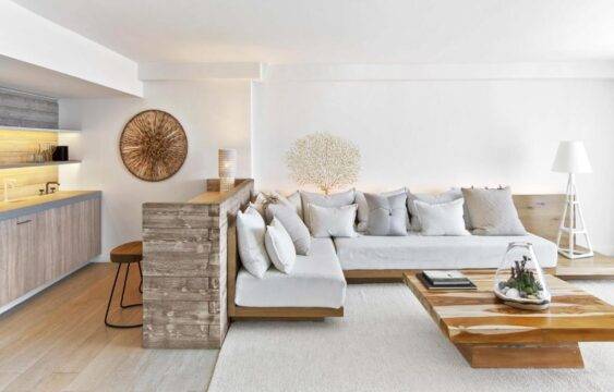A modern living room features a spacious sectional sofa with white cushions and a low wooden coffee table, creating a serene and minimalist aesthetic with natural textures.