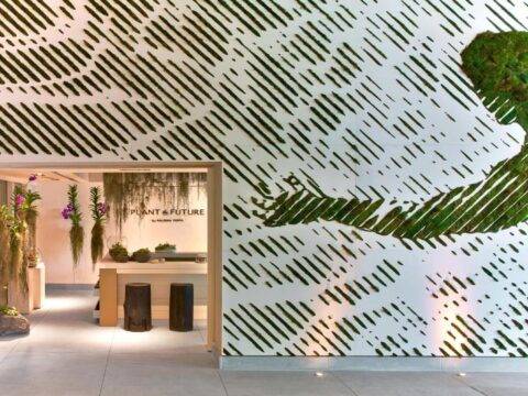 Modern interior design featuring a living green wall with a diagonal pattern and the text "PLANT & FUTURE" above a counter with stools.