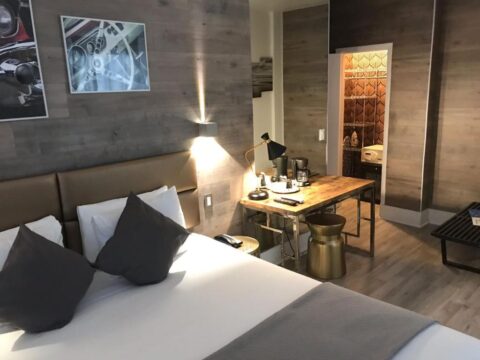 Modern hotel room with a king-size bed, wooden accent walls, and a stylish desk with a coffee maker.