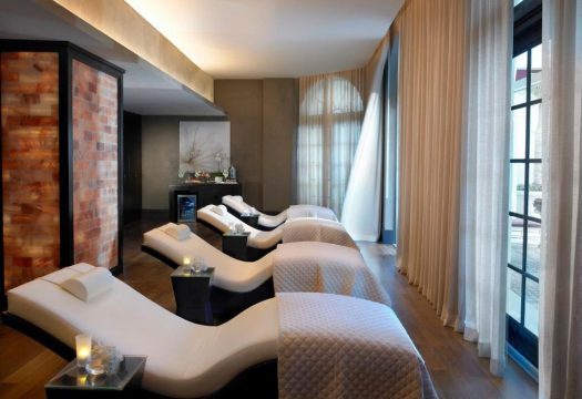 Relaxing spa lounge with plush white recliners, soft ambient lighting, and a Himalayan salt wall, perfect for a luxury spa experience.