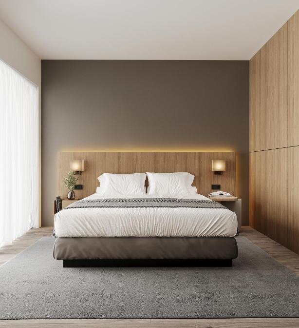 Modern bedroom with a king-size bed featuring white linens, flanked by minimalist nightstands and wall-mounted lamps. A warm, wooden accent wall and built-in closet add to the cozy, contemporary hotel room aesthetic.